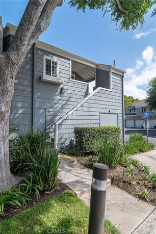 Front view of a two-story residential building with gray siding and an external staircase.