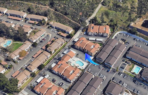 Aerial view of residential area with multiple buildings and parking spaces.