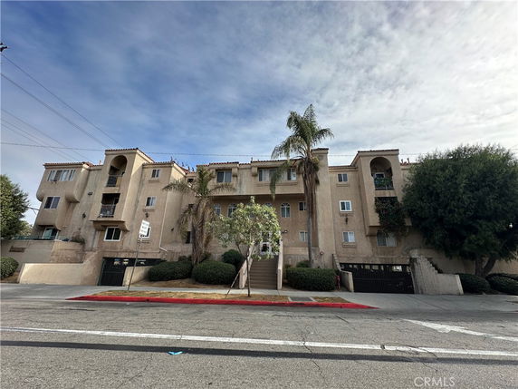 Front view of a multi-story apartment building with balconies and staircases.