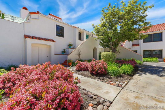 Front view of a two-story house with white stucco walls and red tile roof.