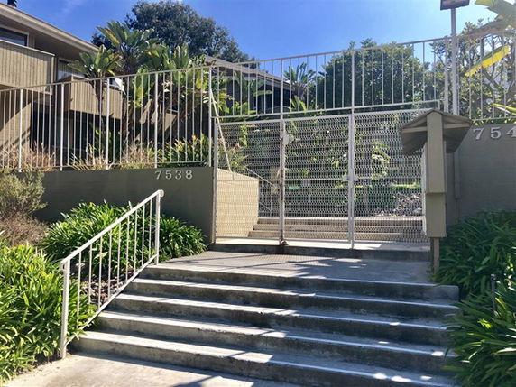Front view of a residential building with a gated entrance and staircase.