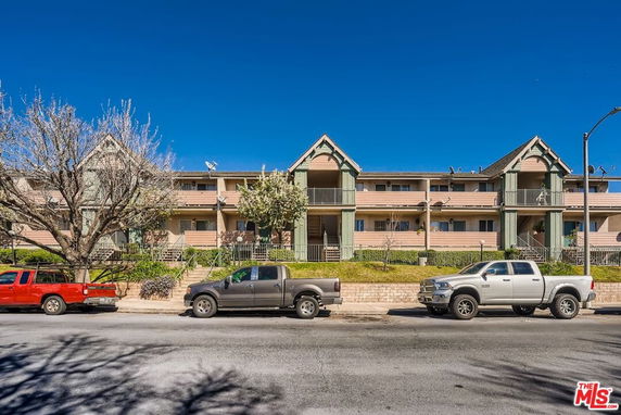 Front view of a two-story residential building with vehicles parked in front.