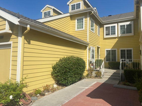 Front view of a two-story yellow house with multiple gables and windows.