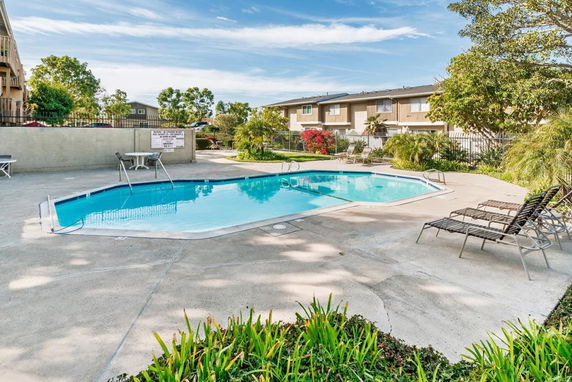 Outdoor swimming pool area with surrounding chairs and greenery.