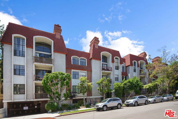 Front view of a multi-story residential building with red roof and balconies.