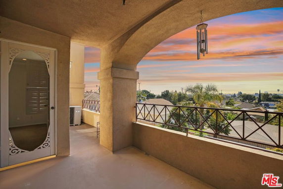 Balcony with railing providing a panoramic view of a neighborhood under a colorful sky.