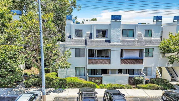 Front view of a multi-story residential building with balconies and flat roof.