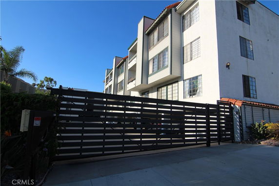 Front view of a multi-story residential building with a gated entrance.