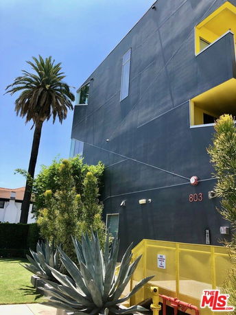 Front view of a modern multi-story building with geometric design and contrasting yellow accents.