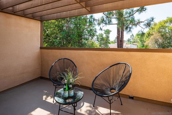 Outdoor patio area with two chairs and table overlooking greenery.
