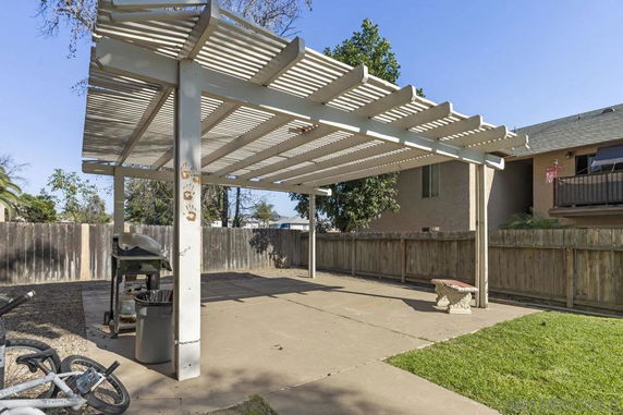 Outdoor area with a pergola structure and a barbecue grill.