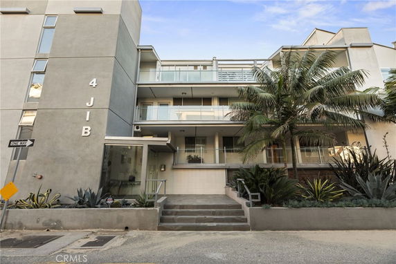 Front view of a modern multi-story building with balconies and glass railings.
