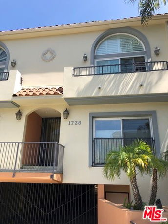 Front view of a multi-story house with balconies and arched windows.