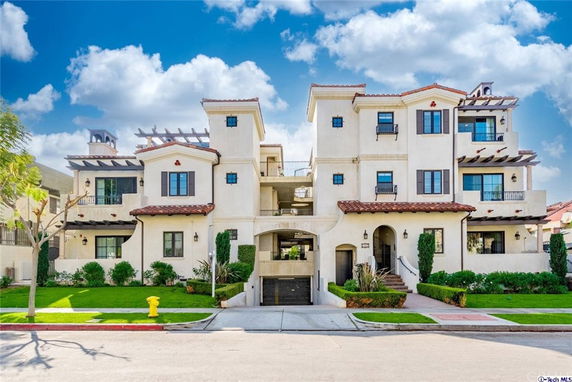 Front view of a multi-story residential building with balconies and a garage entrance.