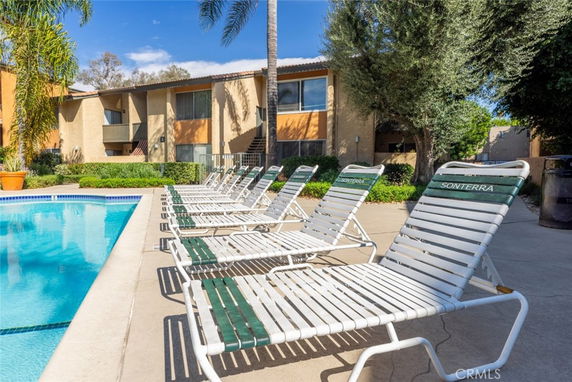 Outdoor swimming pool area with lounge chairs and surrounding apartment buildings.