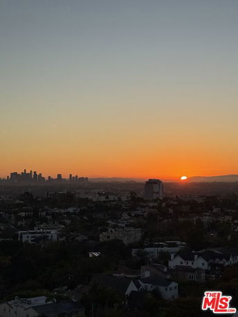 Wide-angle view of a cityscape at sunset with buildings silhouetted against the sky.