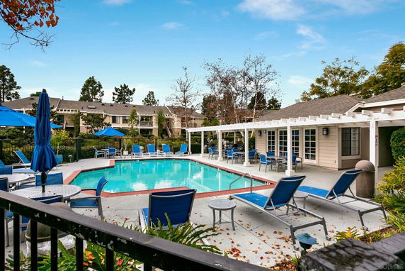 Outdoor swimming pool area with seating and umbrellas.