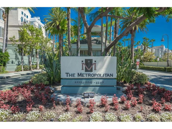 Entrance sign of a residential complex named 'The Metropolitan' with surrounding landscape.