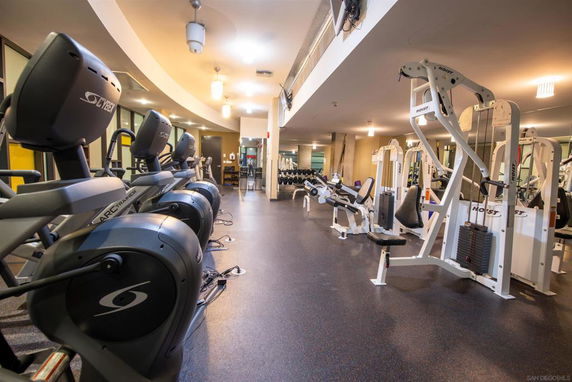 Indoor gym area with various exercise equipment including treadmills and weight machines.