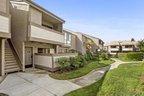 Front view of a multi-story apartment building with balconies and a garden pathway.