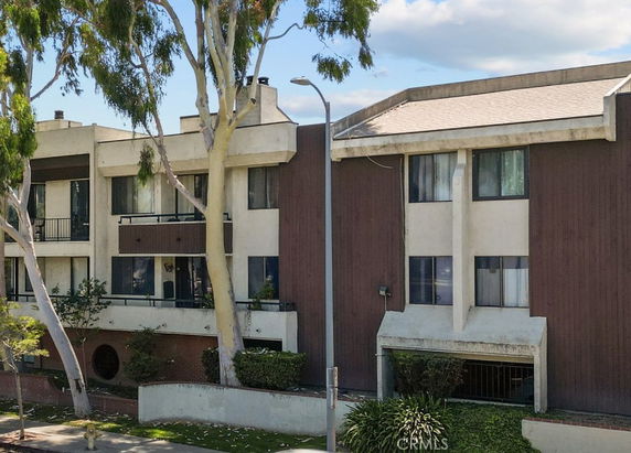 Front view of a multi-story residential building with balconies and large windows.