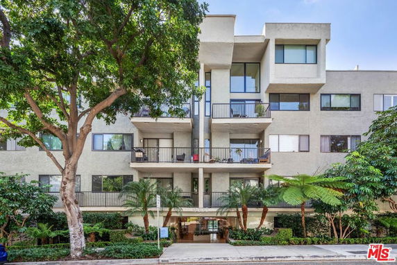 Front view of a multi-story residential building with balconies and large windows.