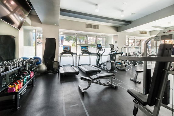 Indoor gym with exercise equipment including treadmills and weights.