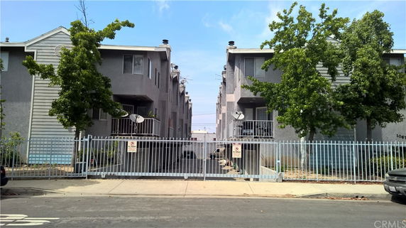 Front view of a multi-story residential building with a gated entrance.
