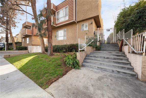 Front view of a multi-story residential building with stairs leading to an entrance.