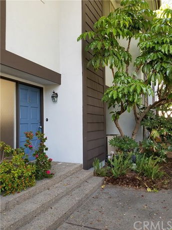 Front view of a house with a blue door and surrounding foliage.