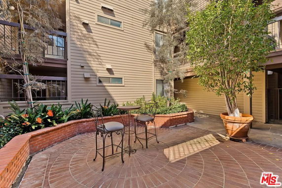 Exterior view of a multi-story building with balconies and a round brick patio area.