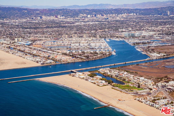 Panoramic view of a coastal city with beachfront, waterways, and cityscape in the background.