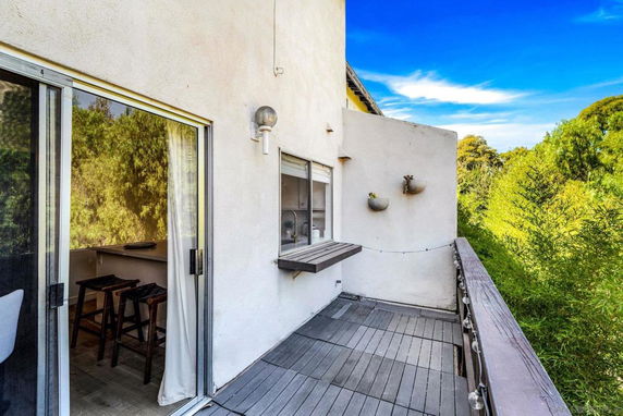 View from a balcony with wooden railing, showing a lush green surrounding.