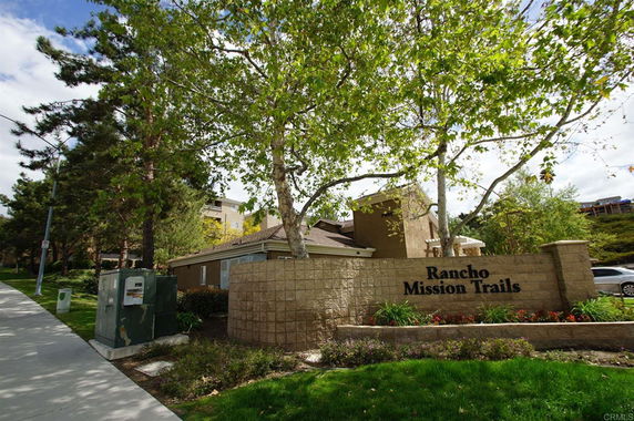 View of a building with a sign for Rancho Mission Trails surrounded by trees.