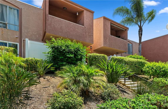 Front view of a multi-story building with balconies and a garden area.