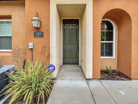 Front view of a house entrance with a green door and arched window.
