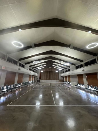 Large indoor recreational area with lined floor and chairs along the walls for activities.