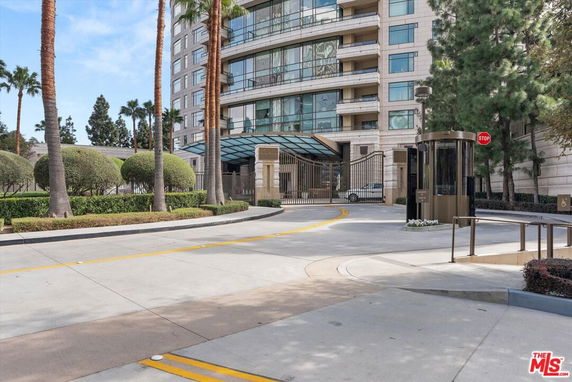 Front view of a multi-story building with gated entrance and security booth.