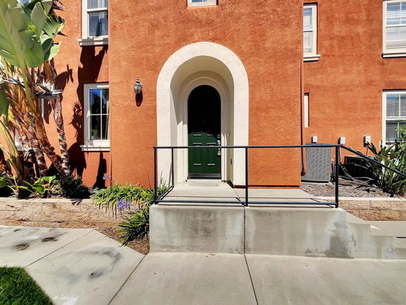 Front view of a house with an arched entrance and red-orange facade.