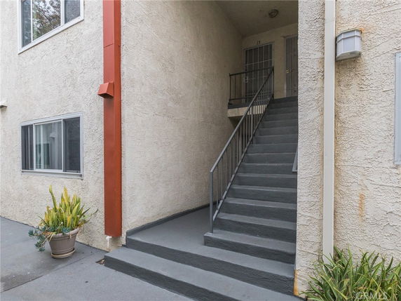 Front view of an apartment building entrance with stairs leading to the second floor.