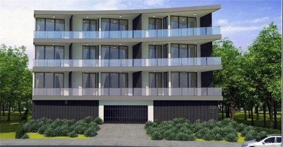 Front view of a modern multi-story building with glass balconies.