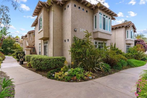 Front view of a multi-story building with stucco exterior and bay windows.