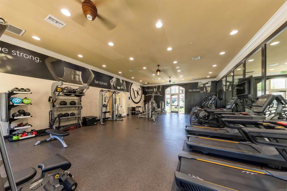 Interior view of a gym with exercise equipment including treadmills and weight machines.