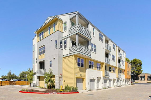 Front view of a multi-story apartment building with balconies and garage entrances.