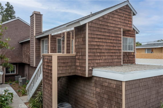 Front view of a multi-level house with shingle siding and a prominent chimney.