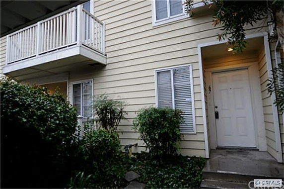 Front view of a two-story house with a small balcony and white front door.