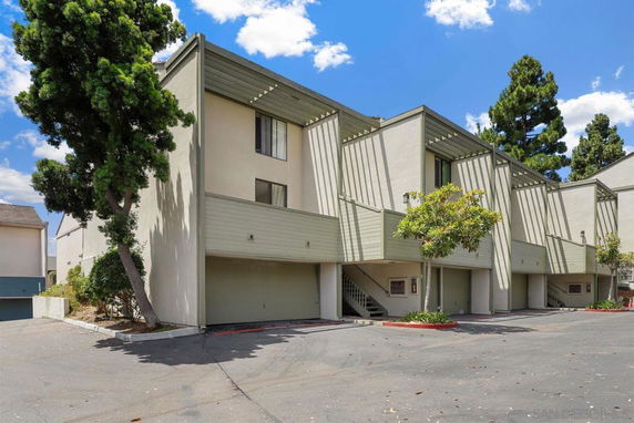 Front view of a multi-story residential building with covered parking and external staircases.