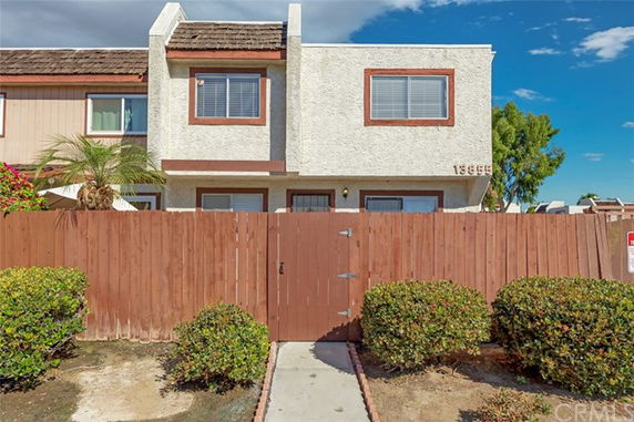 Front view of a two-story house with a wooden fence and gated entrance.