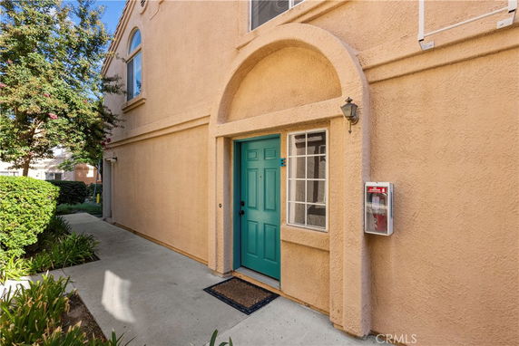 Exterior view of a building entrance with a turquoise door and arched frame.
