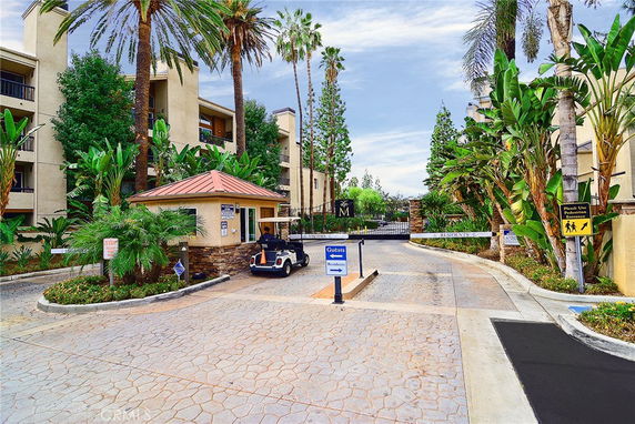Entrance view of a residential complex with a security gate and security booth.